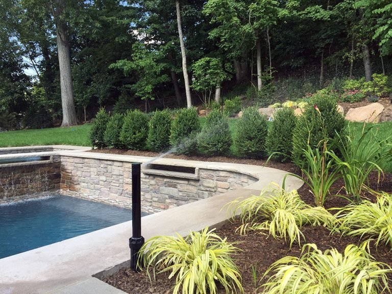 Green Park sprinkler installation beside a landscaped pool in Livingston, New Jersey